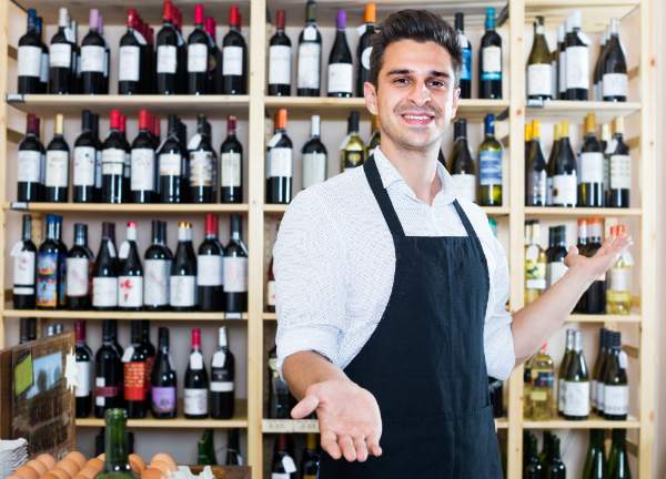 Verkaeufer steht vor einem Weinregal